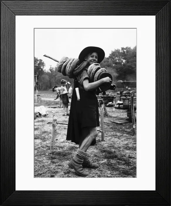 Framed Print : A scout is carrying holed bread with a pole through the centre of them on his shoulder