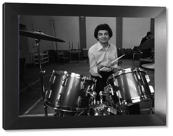 Entertainer Rowan Atkinson practices on drum kit 1980