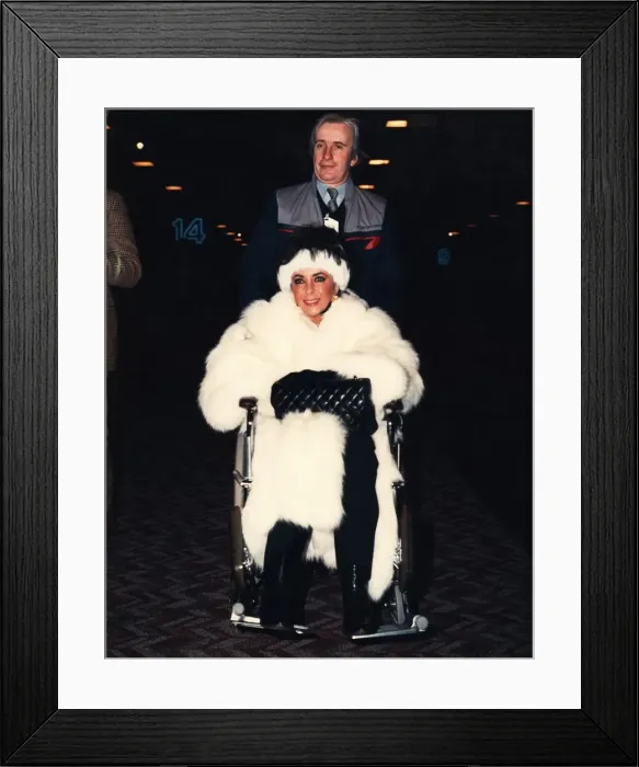 Framed Print : Liz Taylor is pushed through Heathrow airport ijn a wheelchair Framed Print : Liz Taylor is pushed through Heathrow airport ijn a wheelchair