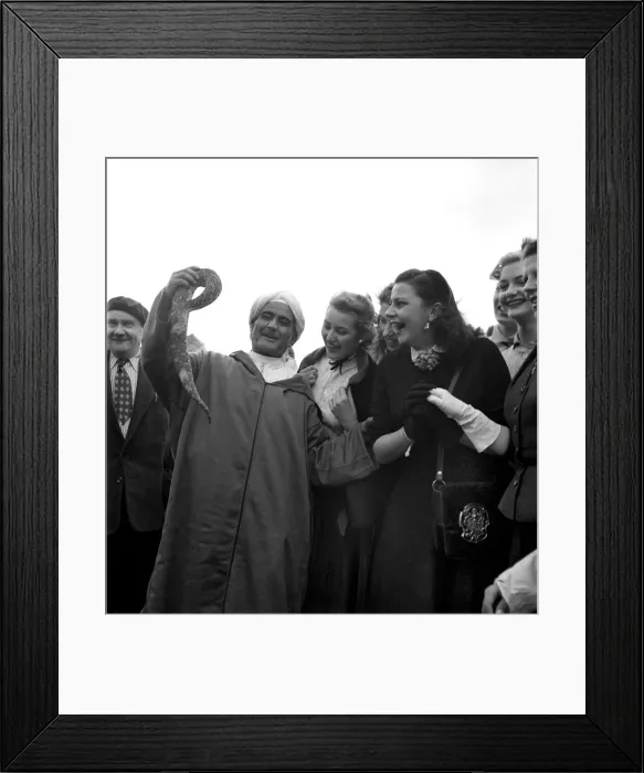 Framed Print : A local man shows off a snake to a group of fascinated French actresses during their Framed Print : A local man shows off a snake to a group of fascinated French actresses during their