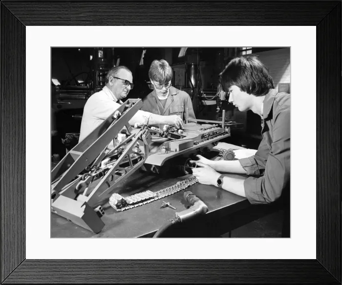 Framed Print : Instructor Jack Laybourn works on a model of an armoured bridgelayer with apprentices Framed Print : Instructor Jack Laybourn works on a model of an armoured bridgelayer with apprentices