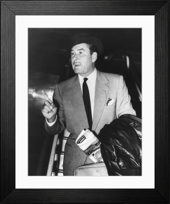 Framed Print : Errol Flynn pointing his finger and holding a suitcase and a news paper with a black