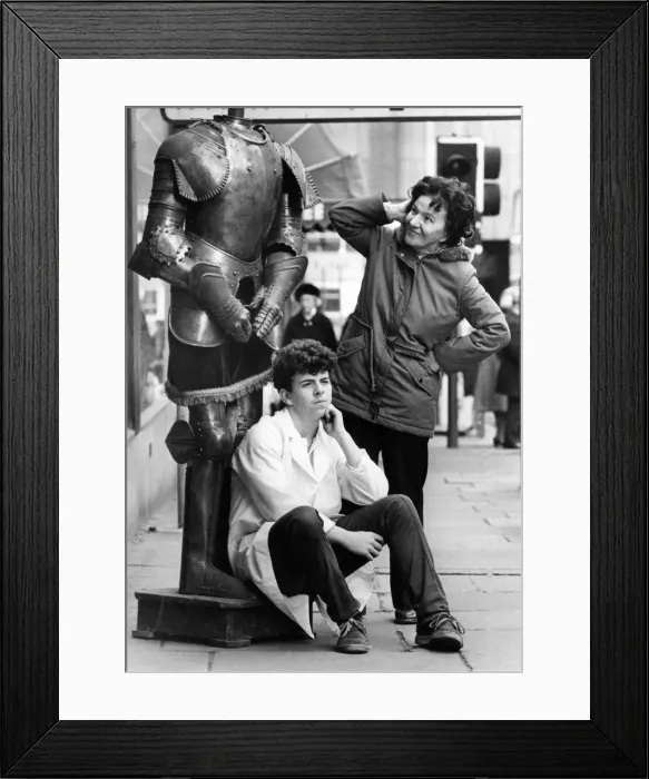 Framed Print : Sales assistant Tommy Frances guards a suit of armour as passers by look in in puzzlement Framed Print : Sales assistant Tommy Frances guards a suit of armour as passers by look in in puzzlement