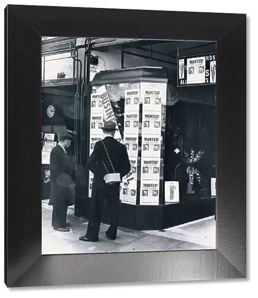 A passer-by look at a tailor shop window plastered with copies of the Daily Mirror Hitler