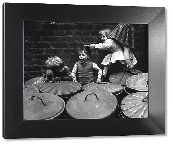 Children playing dustbins on a slum housing estate 1st June 1962