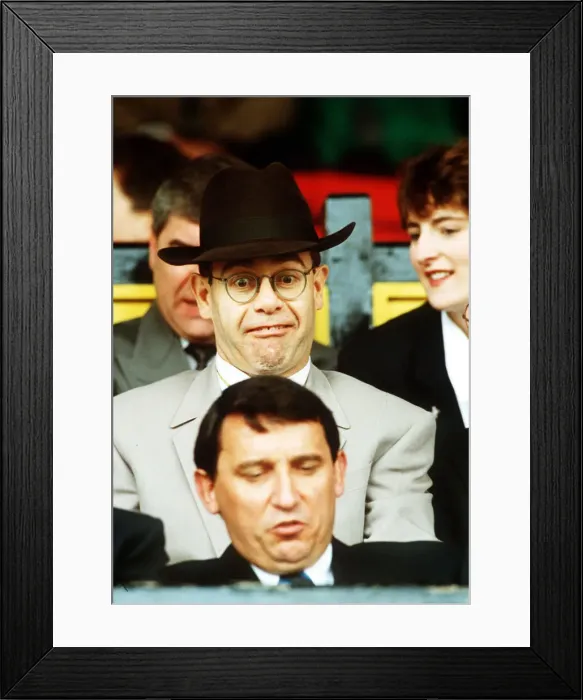 Framed Print : Elton John Singer & Chairman of Watford FC pulls a funny face at Manager Graham Taylor
