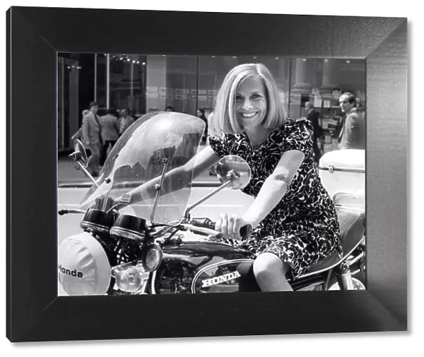 Actress Honor Blackman posing on a motorbike