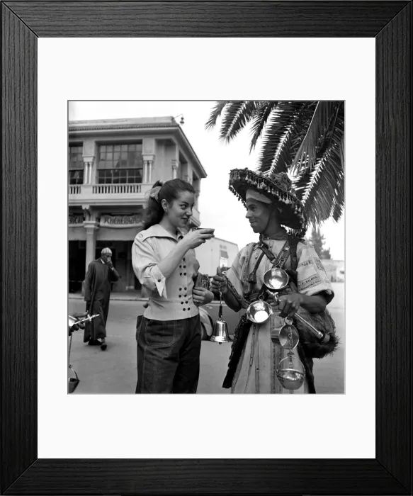 Framed Print : French actress buys a drink of water from a local vendor in the town of