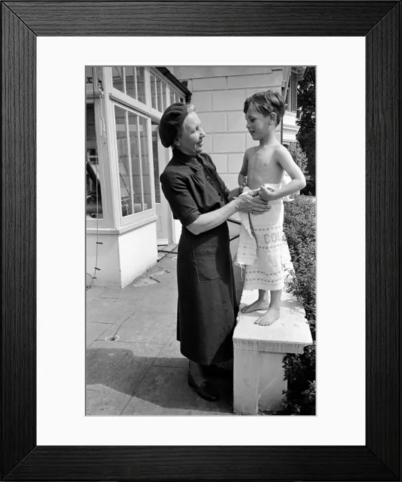 Framed Print : Mrs Stewart of the W. V. S. acts as godmother to a child at the Hollyshaw Nursery