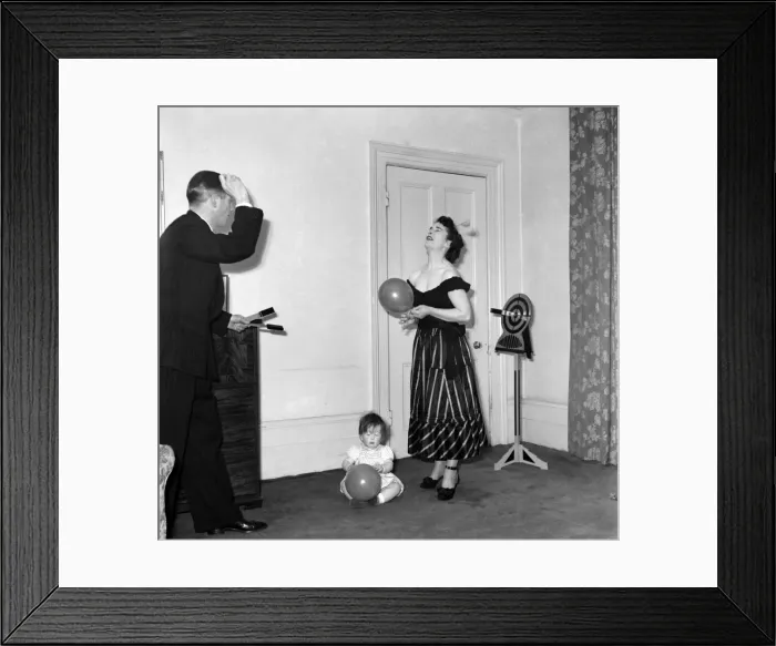 Framed Print : Illusionist Jon Evans practises his knife throwing with his partner and child Framed Print : Illusionist Jon Evans practises his knife throwing with his partner and child