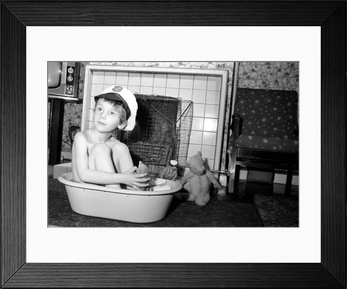 Framed Print : A little boy wearing a sailors cap as he has a bath by the fire Framed Print : A little boy wearing a sailors cap as he has a bath by the fire