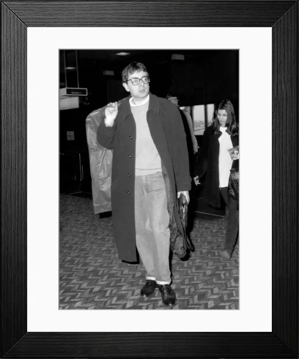 Framed Print : Rowan Atkinson departing from Heathrow Airport with mystery girl believed to be called Framed Print : Rowan Atkinson departing from Heathrow Airport with mystery girl believed to be called