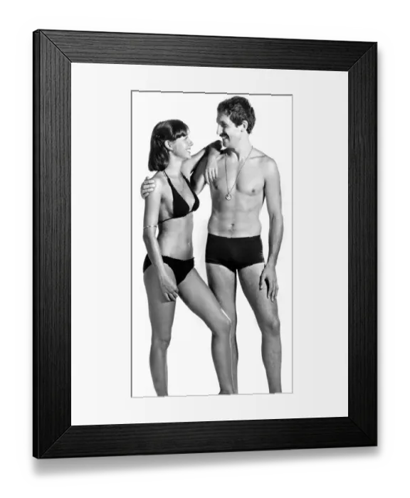 Framed Print : Woman wearing a bikini poses with a man in swimming trunks