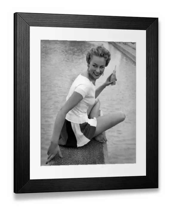 Framed Print : Clothing Beach. Model sits by the water with a drink wearing white t-shirt Framed Print : Clothing Beach. Model sits by the water with a drink wearing white t-shirt
