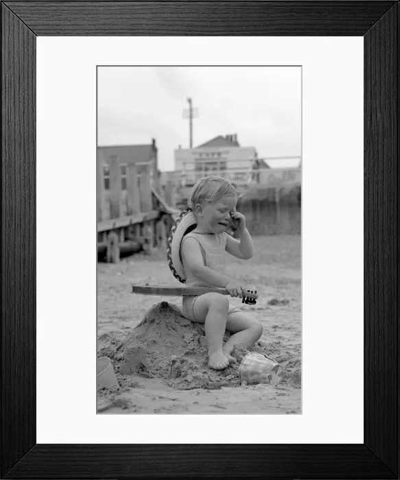 Framed Print : A small boy tired and over excited sitting on the remains of his sand castles crying Framed Print : A small boy tired and over excited sitting on the remains of his sand castles crying