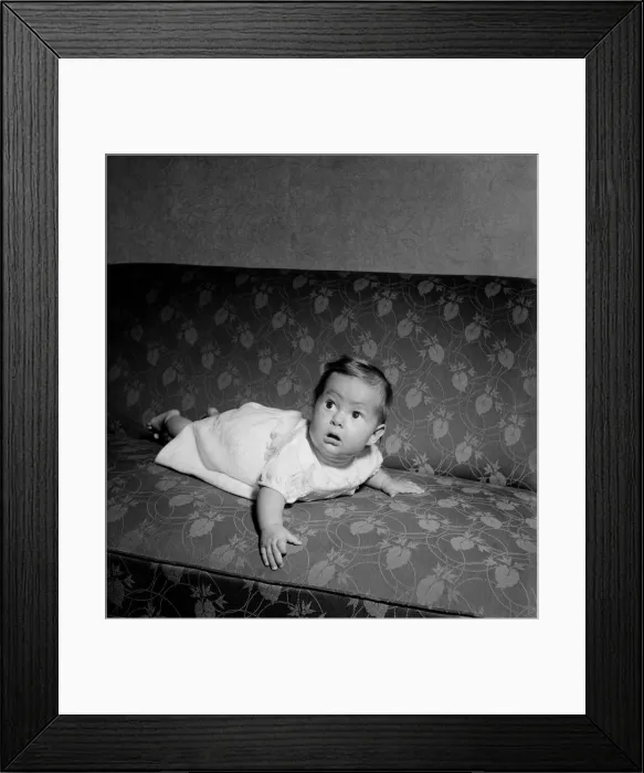 Framed Print : Baby crawling on the sofa at his home. August 1952 C3999
