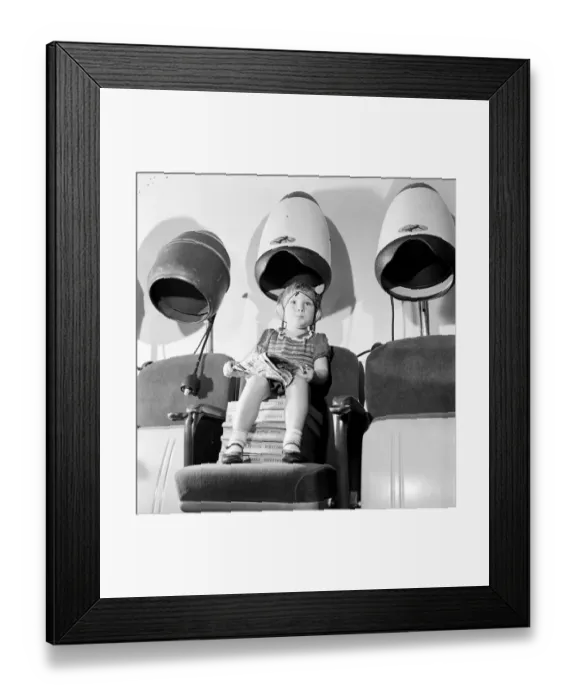 Framed Print : Young girl sitting with her head under a dryer at her local hairdressers August Framed Print : Young girl sitting with her head under a dryer at her local hairdressers August