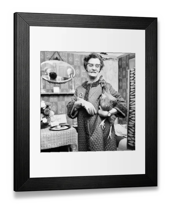 Framed Print : People: Humour: Women: Woman at home holding a chicken in one hand
