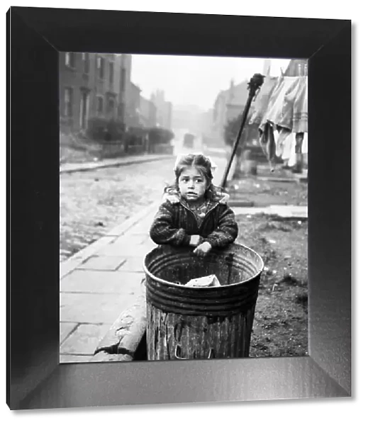 Little girl stands by a dustbin in a Bradford Slum. November 1953 D6539