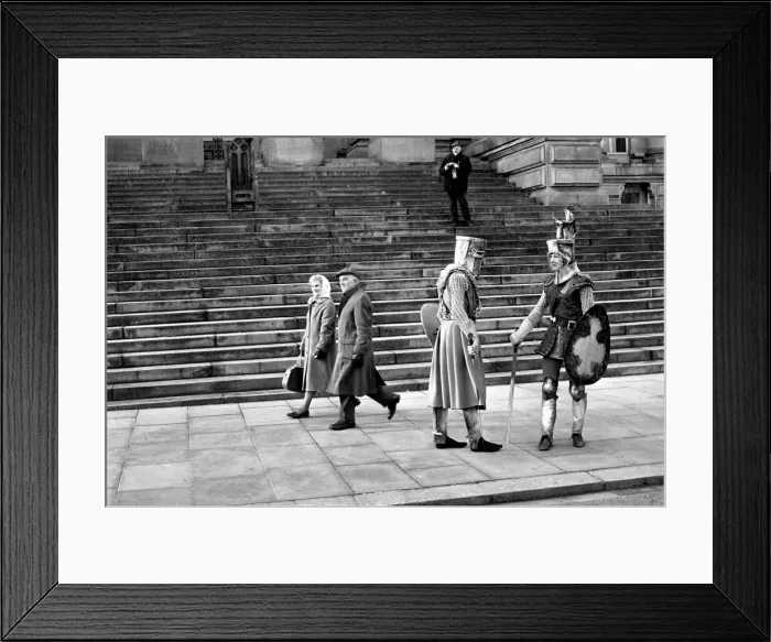 Framed Print : Shoppers hurry past the Town Hall steps as a couple of medieval knights are locked in
