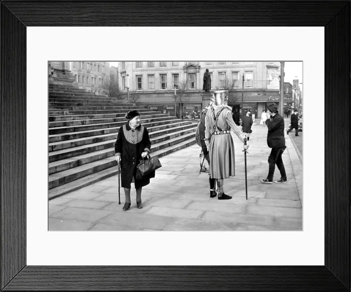 Framed Print : Shoppers hurry past the Town Hall steps as a couple of medieval knights are locked in Framed Print : Shoppers hurry past the Town Hall steps as a couple of medieval knights are locked in