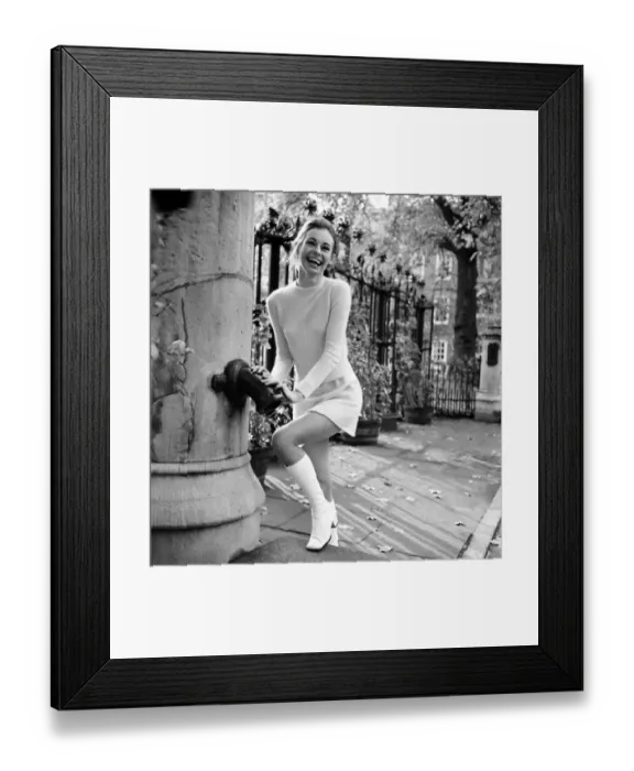 Framed Print : Woman wearing matching top, mini skirt and knee high looks poses for pictures