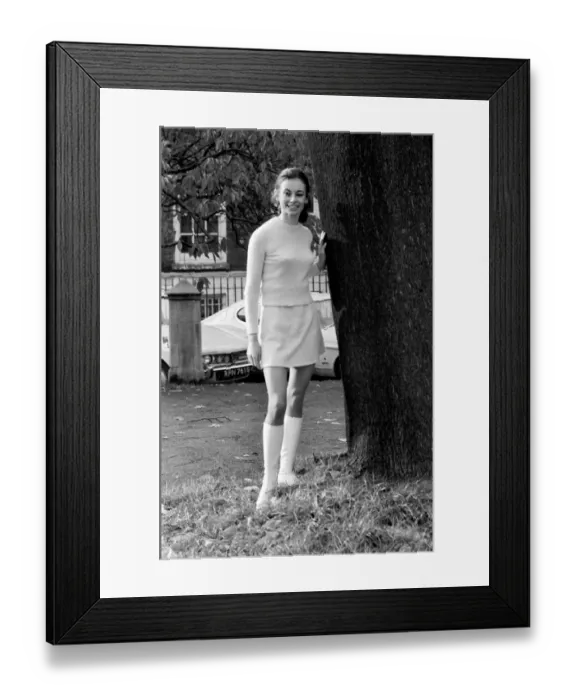 Framed Print : Woman wearing matching top, mini skirt and knee high looks poses for pictures