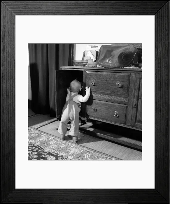 Framed Print : Baby boy looking in the cupboards at his home. October 1952 C5534-001 Framed Print : Baby boy looking in the cupboards at his home. October 1952 C5534-001