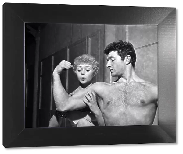 Strong man of Television Arthur Mason showing of his muscles to girlfriend Vera Day