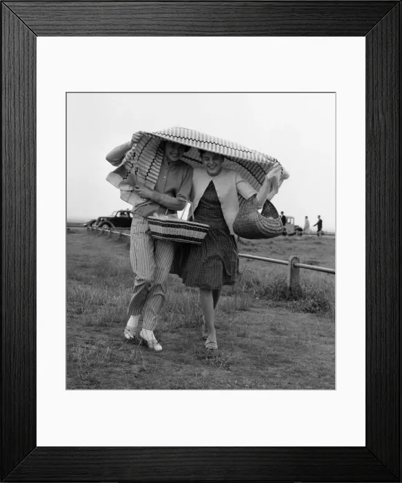 Framed Print : Holidaymakers covering their heads run for cover after being caught in a shower