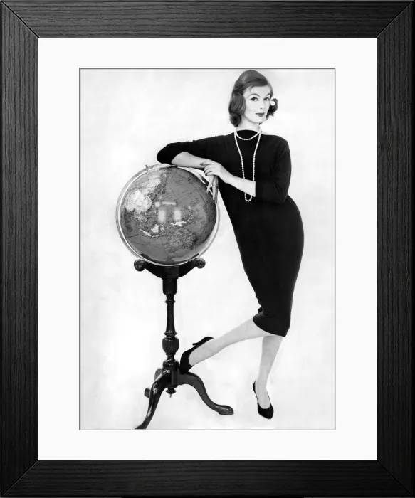 Framed Print : Woman wearing long dress poses leaning against a globe on a stand Framed Print : Woman wearing long dress poses leaning against a globe on a stand