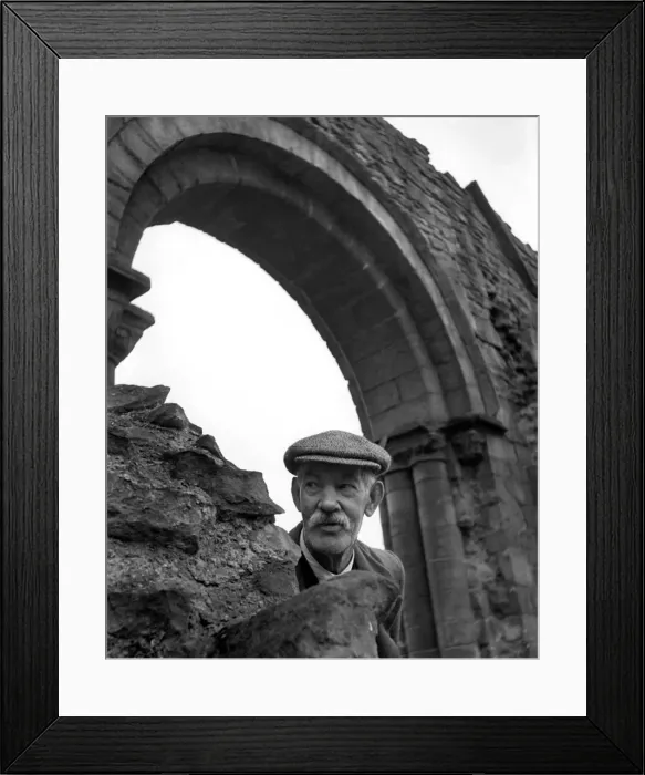 Framed Print : An old man wearing a flatcap peeping out from underneath an archway Framed Print : An old man wearing a flatcap peeping out from underneath an archway