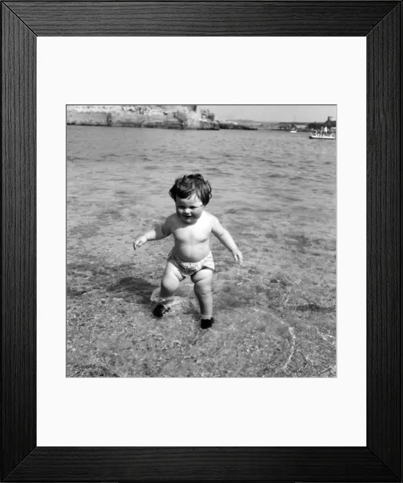 Framed Print : Families on the beach at Plymouth: Baby girl having her first dip in the sea Framed Print : Families on the beach at Plymouth: Baby girl having her first dip in the sea