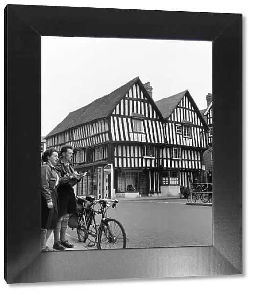 Man and woman sightseeing in an English town with Tudor style houses. October 1952 C5252