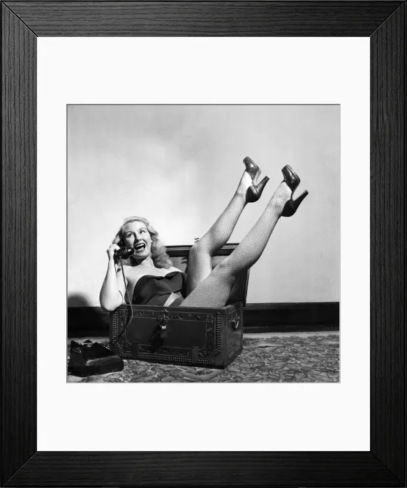 Framed Print : Actress June Cochrane sitting in a chest talking on the telephone. October 1952 C5181