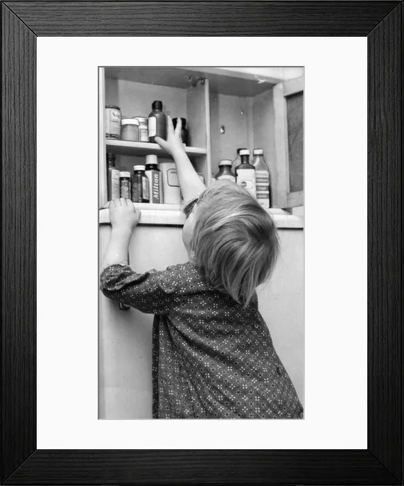 Framed Print : Death lurking in a bottle on the bathroom shelf - A young girl reaches for a bottle of Framed Print : Death lurking in a bottle on the bathroom shelf - A young girl reaches for a bottle of