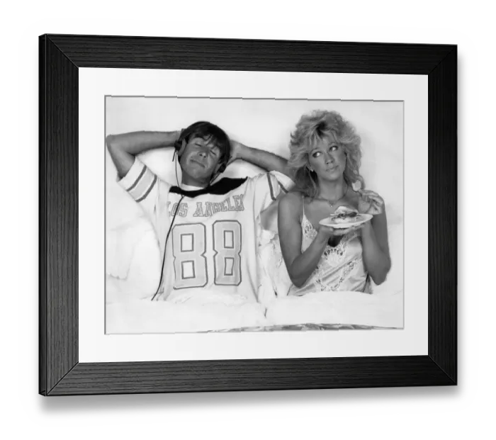 Framed Print : Couple in bed, He listens to music while the wife comfort eats October 1986 P009156 Framed Print : Couple in bed, He listens to music while the wife comfort eats October 1986 P009156
