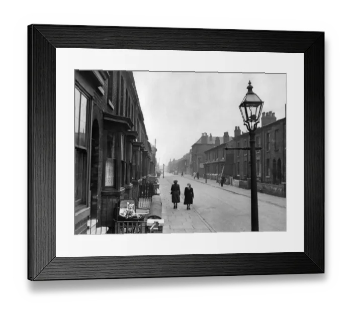 Framed Print : A baby sits in its pram outside the front of a house in a terraced street in the Cheetham Framed Print : A baby sits in its pram outside the front of a house in a terraced street in the Cheetham