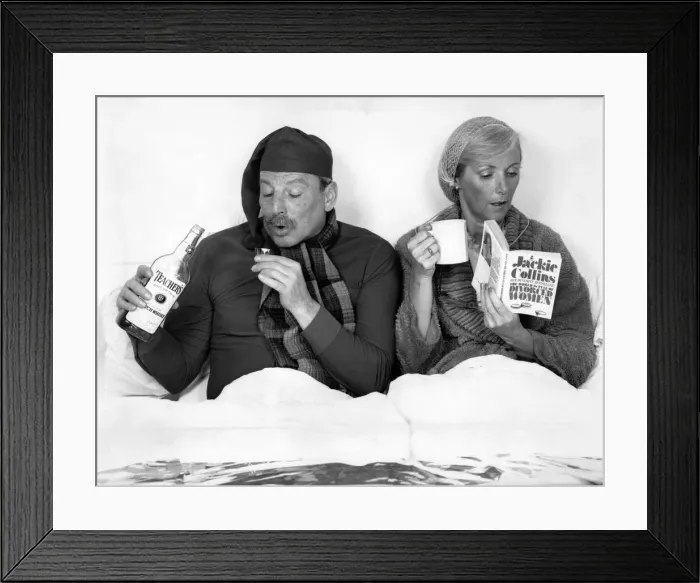 Framed Print : The British at bed time. Husband and wife in bed. He drinks whisky while she reads her