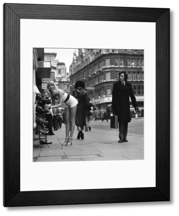 Framed Print : A gentlman admires model Christine Donnas behind as she searches out a new pair of
