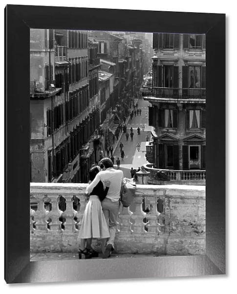 Loving couple look down over a street in the city of Rome, Italy April 1975