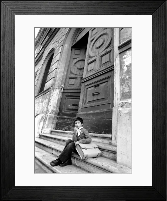 Framed Print : Young child sitting on the steps of an old building in a poor suburb on the outskirts of Framed Print : Young child sitting on the steps of an old building in a poor suburb on the outskirts of