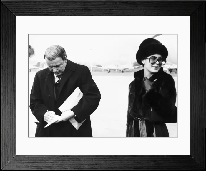 Framed Print : Frank Sinatra Actor and Singer writing on a piece of paper while standing at an airport
