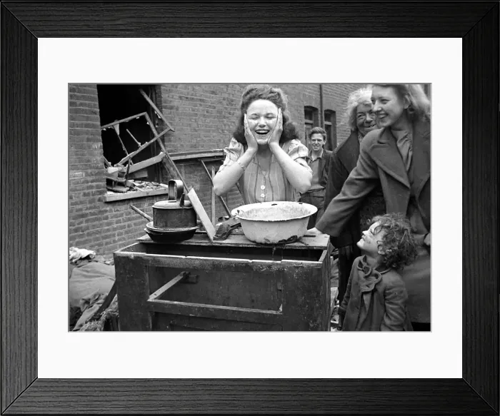 Framed Print : A woman washes her face surrounded by bomb damage on St