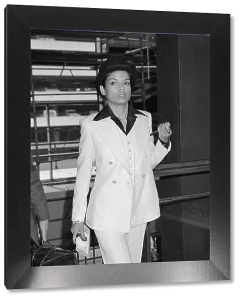 Bianca Jagger, wife of Mick Jagger, in white suit and bowler hat with silver topped cane