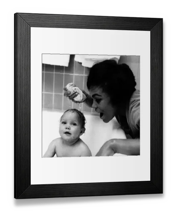 Framed Print : American singer and actress Eartha Kitt, photographed giving her baby girl Kitt a bath