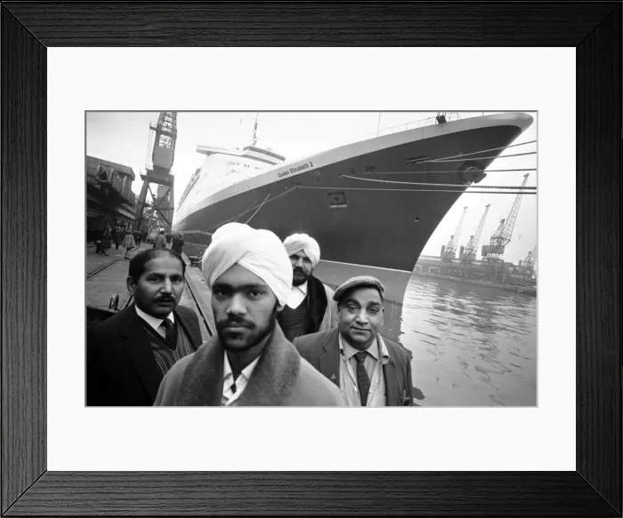 Framed Print : Asian immigrants arriving in Britain by ship, with the famous ocean liner QE2 behind Framed Print : Asian immigrants arriving in Britain by ship, with the famous ocean liner QE2 behind
