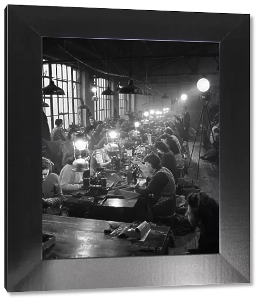 Factory girls at clothing works in East London use candle powered search lights for