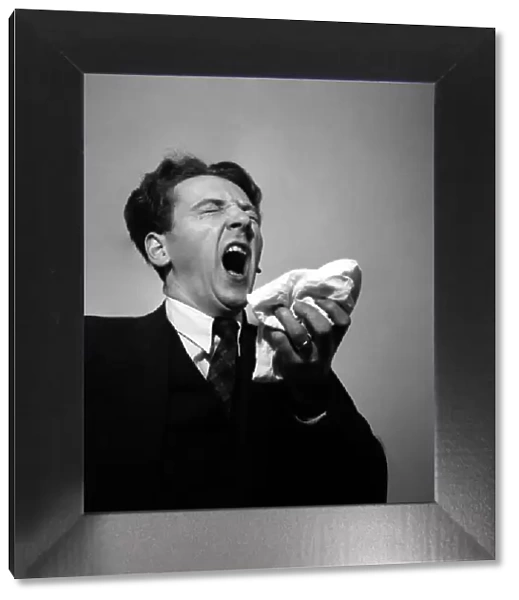 Man holding his handkerchief while sneezing. October 1952 C4925-001
