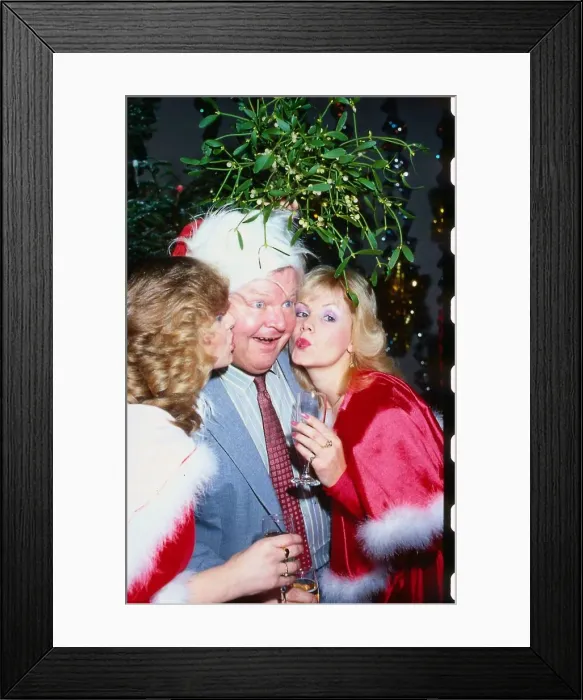 Framed Print : Benny Hill comedian December 1991 Being kissed under mistletoe by two girls Framed Print : Benny Hill comedian December 1991 Being kissed under mistletoe by two girls